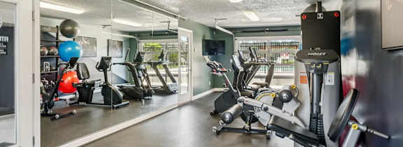 A gym with a variety of equipment including treadmills, weights, and exercise machines.