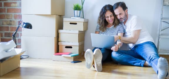 couple looking at laptop surrounded by moving boxes