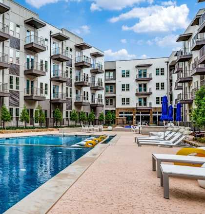 A large swimming pool is surrounded by apartment buildings.