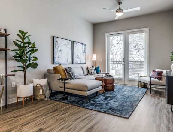 A living room with a couch, chairs, and a ceiling fan.