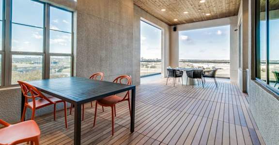 A room with a table and chairs with a view of the beach outside.