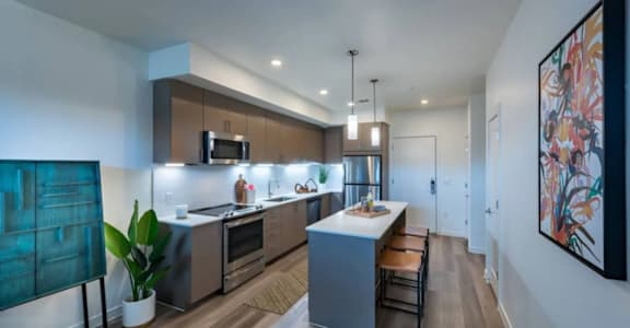 A modern kitchen with a bar stool and a potted plant.