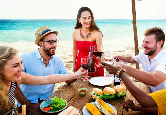 people sitting around a table drinking wine and eating food on the beach at Indian Trace, West Palm Beach Florida