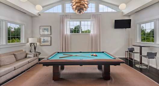 a living room with a pool table and a large window
