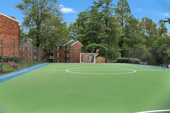 A green basketball court in front of a brick building.