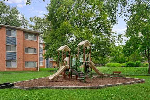 A playground with a slide and a swing set in a grassy area.