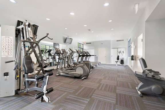 A gym with a variety of equipment including treadmills, weights, and exercise machines.