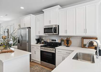 A modern kitchen with white cabinets and stainless steel appliances.