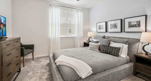 A bedroom with a bed, dresser, and ceiling fan.