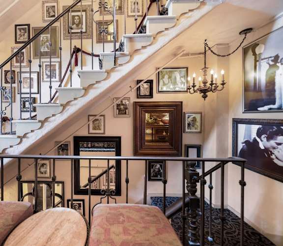 A staircase with a chandelier and pictures on the wall.