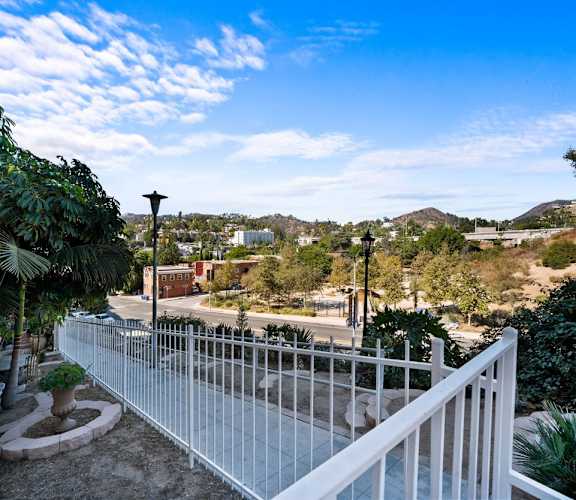 A white fence surrounds a patio with a view of the mountains.
