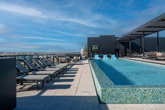 A large swimming pool with sun loungers and a building in the background.
