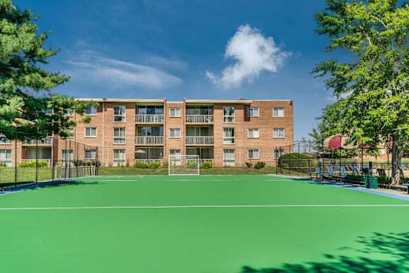 A tennis court in front of a large apartment building.