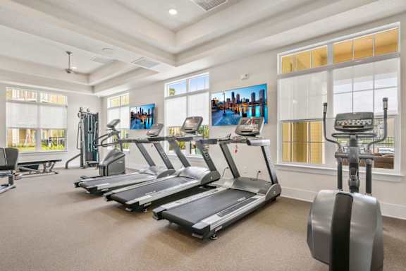 A spacious home gym with treadmills, elliptical machines, and a rowing machine.