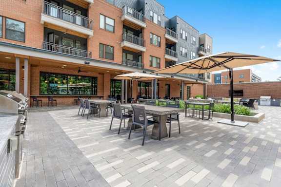 A patio with tables and chairs is surrounded by apartment buildings.