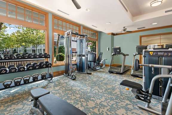 A gym with a variety of equipment including treadmills, weights, and exercise machines.