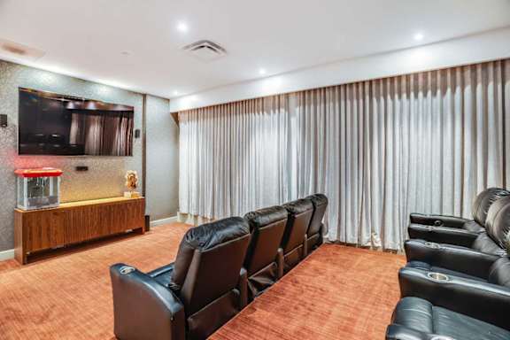 A home theater with black leather chairs and a wooden entertainment center.