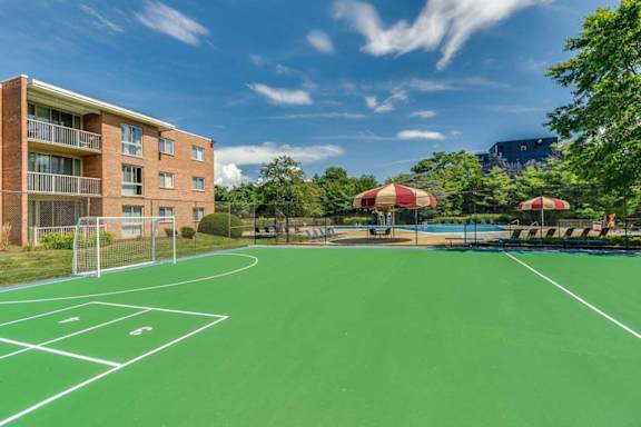 a basketball court in front of a building with a pool