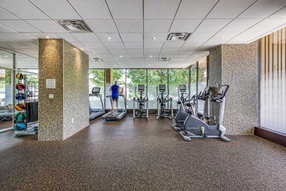 A gym with a variety of exercise equipment including treadmills, stationary bikes, and elliptical machines.