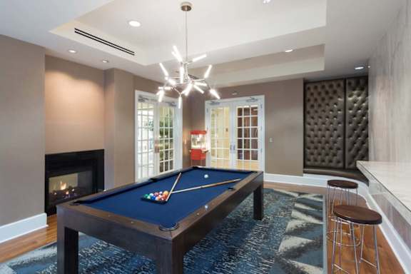 A pool table is in the middle of a room with a fireplace and a bar.