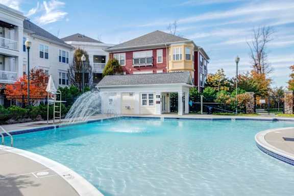 A large swimming pool in front of a multi-story apartment building.
