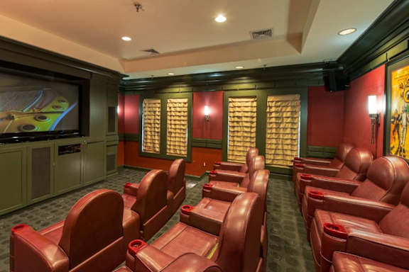 A row of red seats are arranged in front of a large screen.