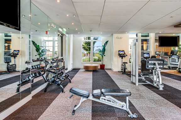 A gym with a variety of equipment including treadmills, weights, and exercise machines.
