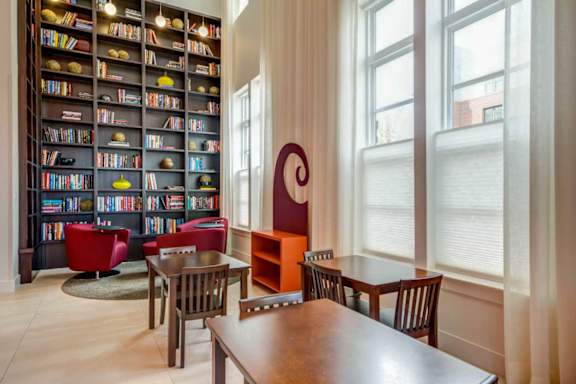 A room with a large bookshelf filled with books and a wooden table with chairs.