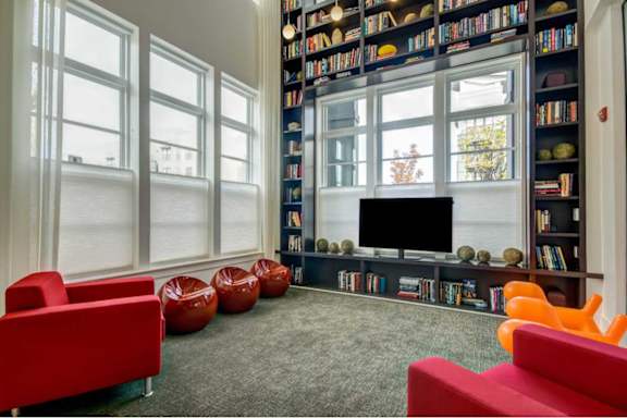 A living room with a large bookshelf filled with books and a flat screen TV.