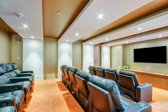 A home theater with black leather seats and a large screen.