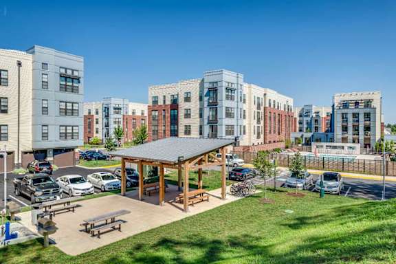 A gazebo is surrounded by a parking lot and apartment buildings.