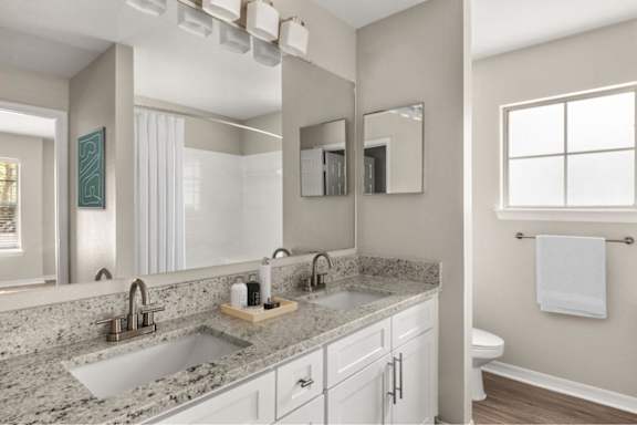 A bathroom with a granite countertop and a large mirror.