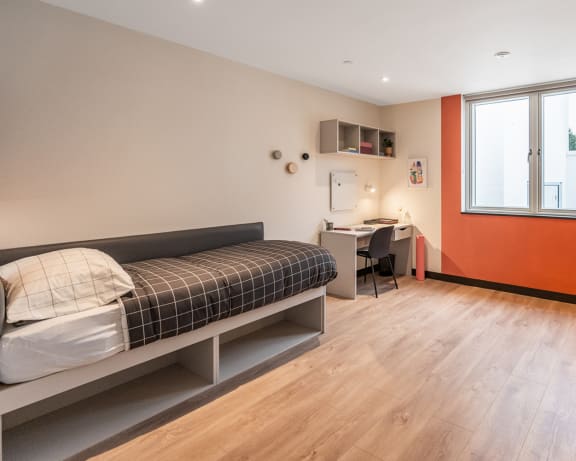 a bedroom with a bed and a desk and a window