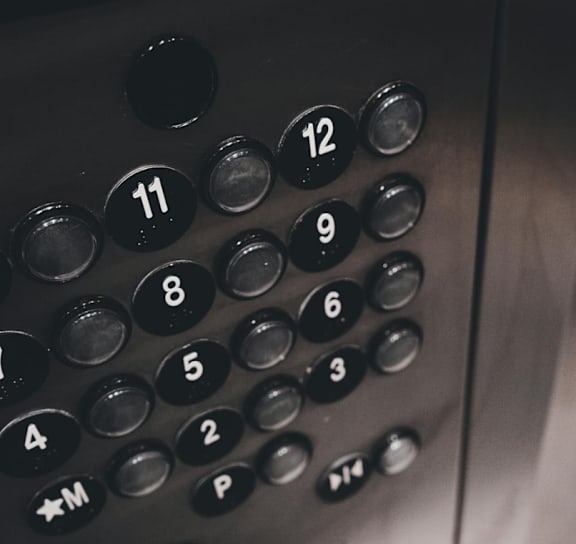 A close up of an elevator control panel with buttons numbered from 1 to 12 and a power button.