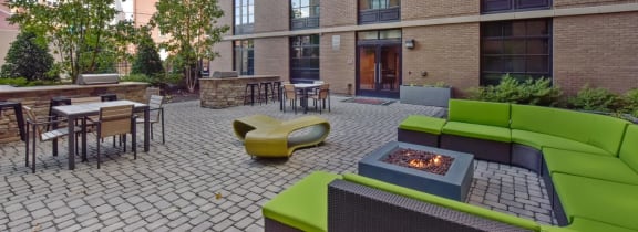 a patio with a fire pit and lounge chairs in front of a brick building