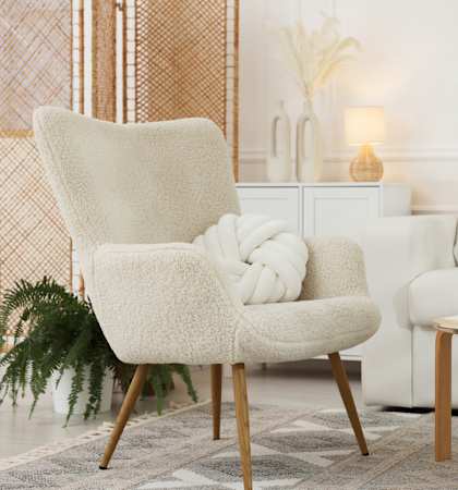 A white chair with a white cushion is in front of a white couch.