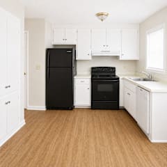 A black refrigerator and oven in a kitchen with white cabinets.