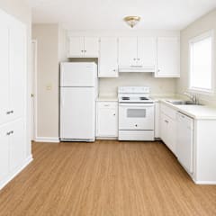 A white kitchen with wooden floors and white appliances.
