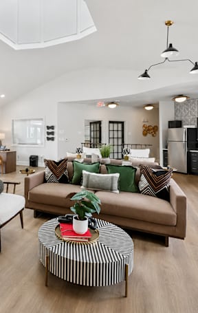 A living room with a brown couch and a striped coffee table.