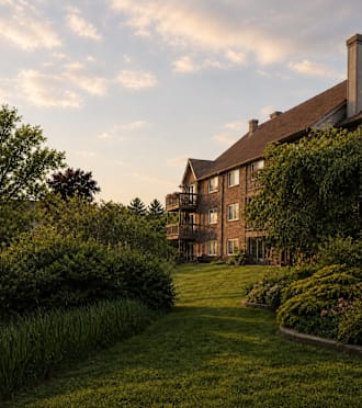 A large house with a well-manicured lawn and a variety of shrubbery.