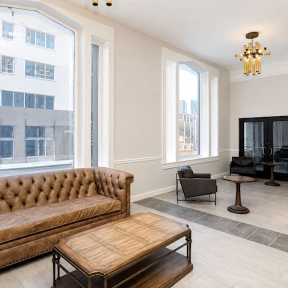 A brown tufted couch sits in a living room with a wooden coffee table in front of it.