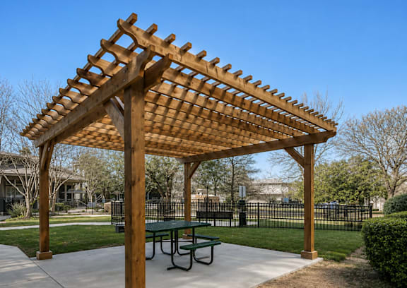 A wooden pergola with a green table underneath it.