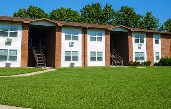 A row of townhouses with a green lawn in front.