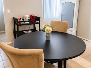 A black table with a vase of flowers on it and two chairs.