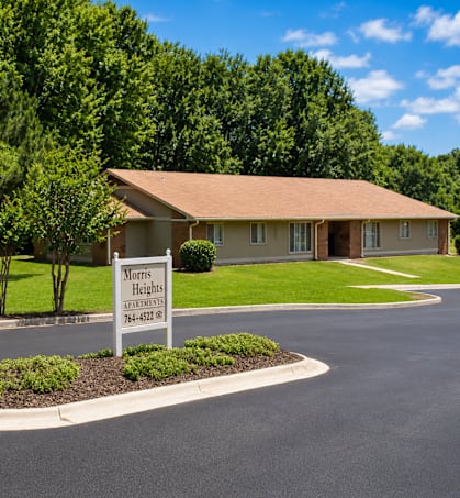 A sign for Morris Heights Apartments is in the foreground of a well-manicured lawn.