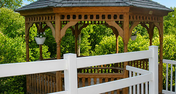 A gazebo with a white fence in front of it.