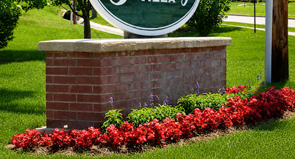 A sign that says Gateway Village in front of a green lawn.
