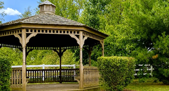 A wooden gazebo with a stone pathway leading to it.