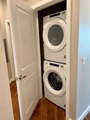 A closet in a hallway with a modern stacked washer and dryer combination.