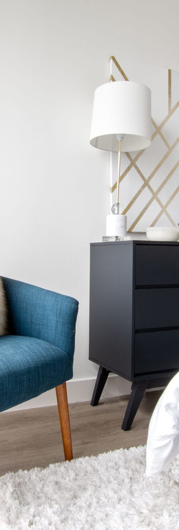 a bedroom with a bed and a blue chair and a black dresser